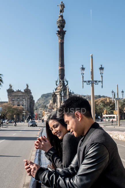 Giovane coppia turistica che guarda il cellulare al monumento Columbus, Spagna — Foto stock