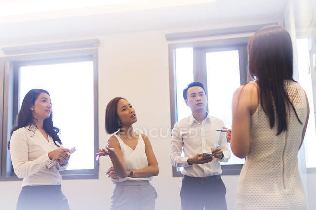 Mujer joven haciendo la presentación a sus colegas en la oficina moderna - foto de stock