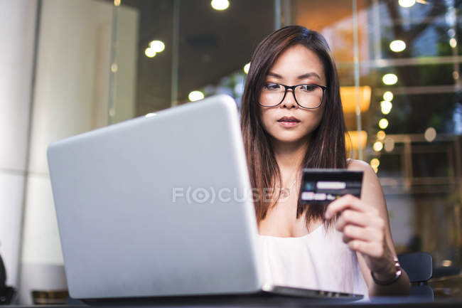Гарненька азіатська дівчина виготовлення a транзакція на її ноутбук . — стокове фото