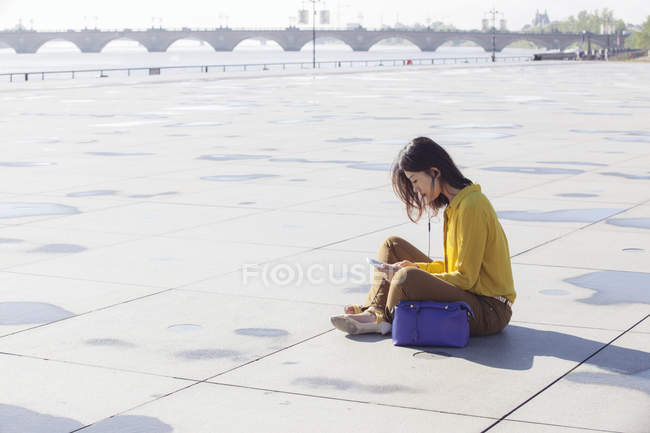 Китайська жінка, що кількість місць на підлозі і за допомогою смартфона — стокове фото