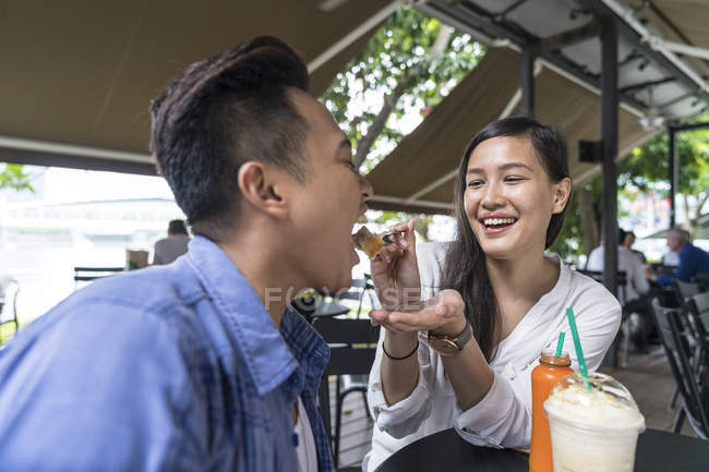 Joven hermosa asiático pareja comer en café - foto de stock