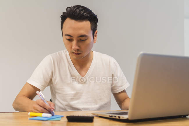 Jeune homme travaillant avec son ordinateur portable dans l'environnement de démarrage — Photo de stock