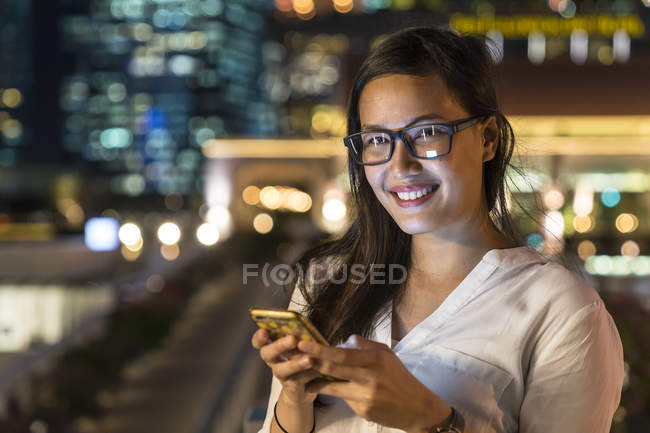 Young beautiful asian woman using smartphone outdoors — Stock Photo