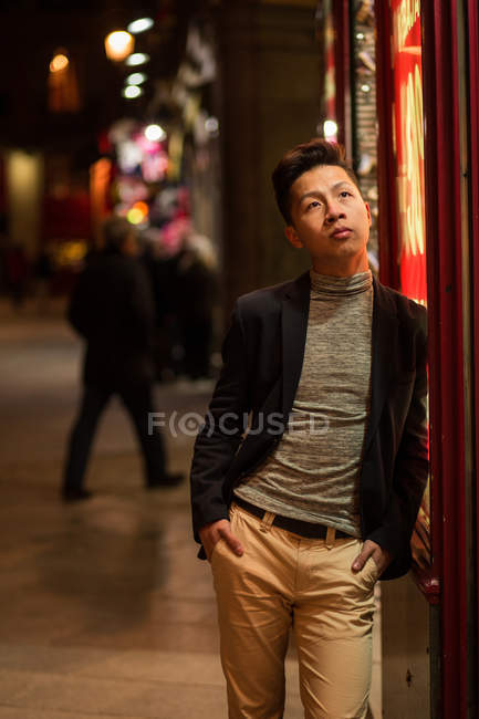 Joven chino casual merodeando por las calles de Madrid por la noche, España - foto de stock