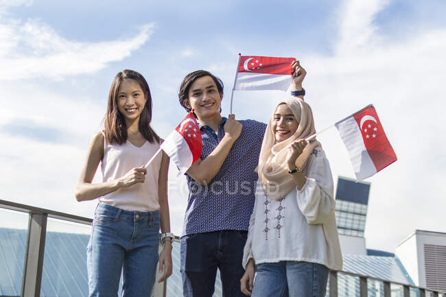 Um grupo de amigos posando com as bandeiras de Singapura. — Fotografia de Stock