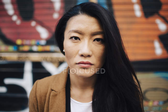 Portrait of attractive asian woman against graffiti — Stock Photo
