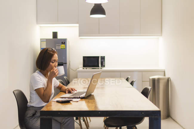 Jovem mulher trabalhando no ambiente de inicialização com laptop — Fotografia de Stock