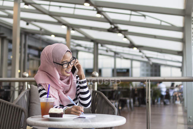 Jovem mulher anotando algumas informações em um café — Fotografia de Stock