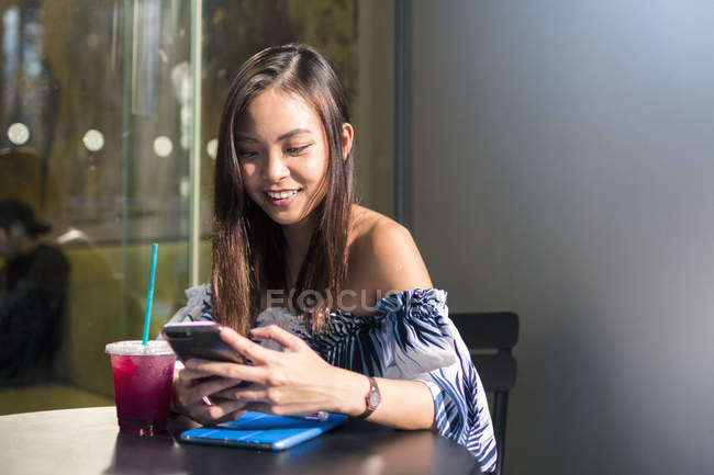 Bastante asiático chica con un teléfono en café - foto de stock