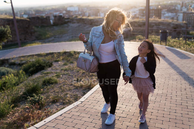 Portrait d'une jeune mère heureuse avec sa fille marchant dans la ville par une journée ensoleillée. — Photo de stock