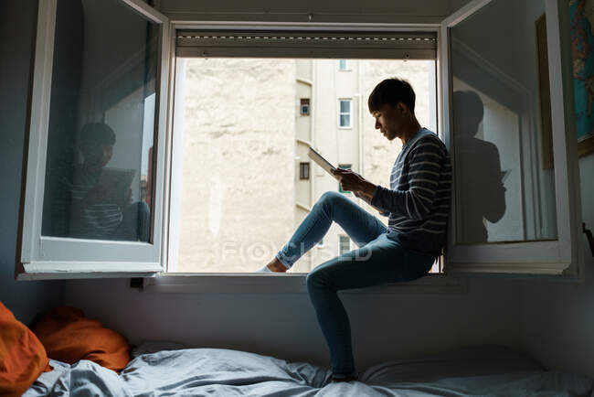 Vista laterale dell'uomo sul davanzale della finestra — Foto stock