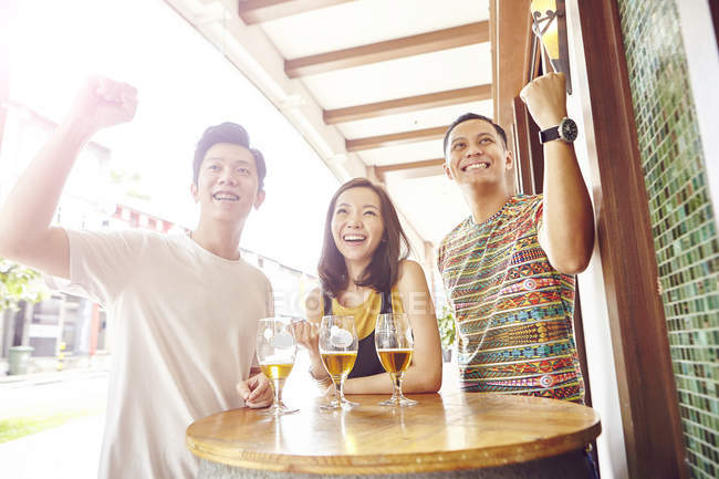 Giovani amici asiatici tifo insieme nel bar — Foto stock
