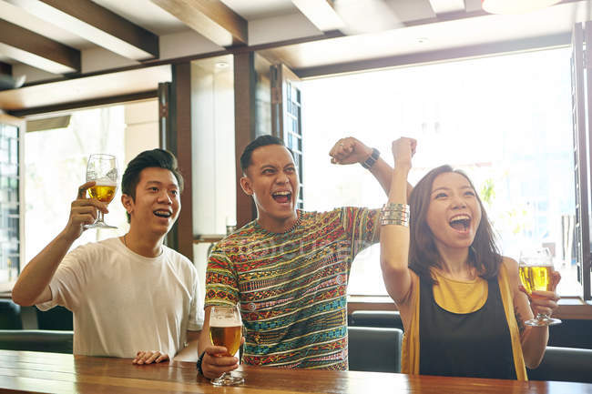Молодые азиатские друзья аплодируют вместе в баре — стоковое фото