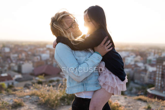 Retrato de la joven madre feliz con su hija en la ciudad en un día soleado . - foto de stock