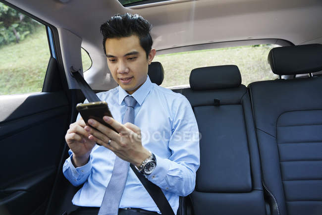 Joven hombre de negocios comprobar móvil en coche - foto de stock