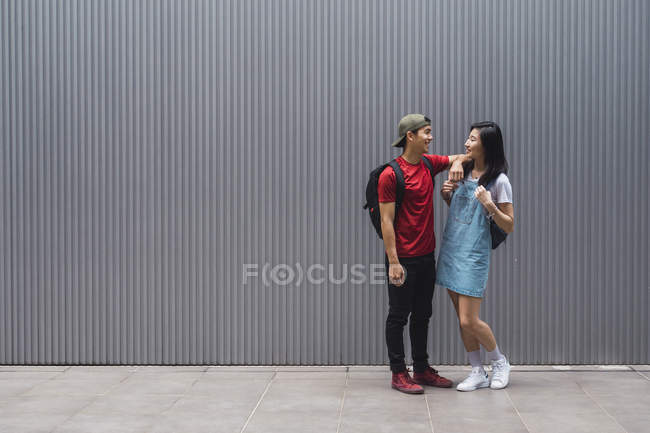 Jovem asiático faculdade estudantes posando contra cinza parede — Fotografia de Stock