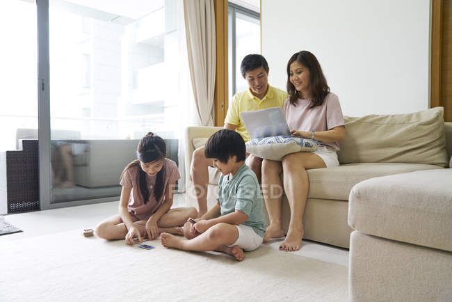 Children playing card games as their parents work on a laptop — Stock Photo