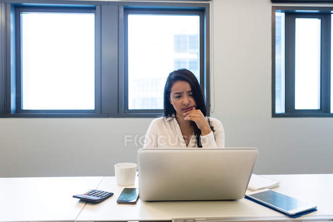 Young woman working on laptop in modern office — Stock Photo