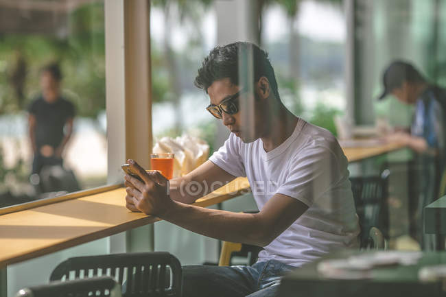 Чоловік користується смартфоном у пляжному клубі Сентоса. — стокове фото