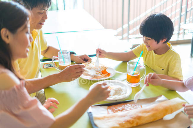 Família comer iguarias indianas no café — Fotografia de Stock