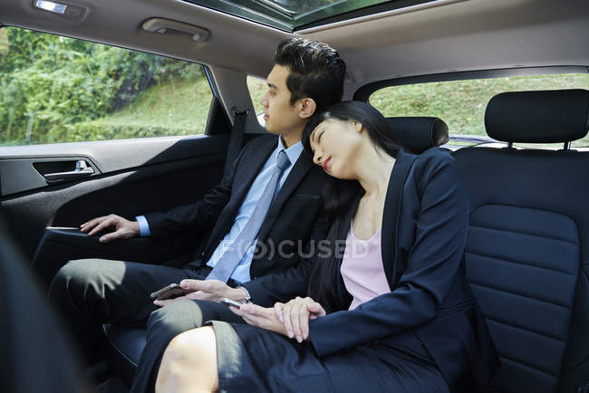 Business couple resting in the back seat of a car — Stock Photo