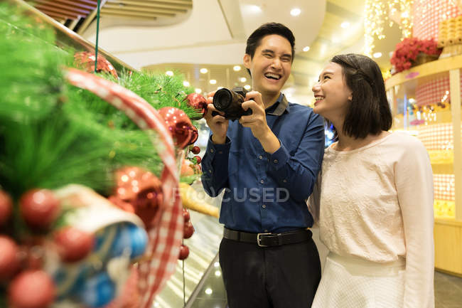 Young attractive asian couple together shopping in mall at christmas — Stock Photo