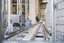 Businessman at conveyor belt in factory — Stock Photo