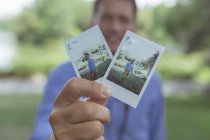 Mains masculines tenant des photos instantanées — Photo de stock