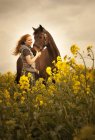 Ritratto di giovane donna felice con il suo cavallo in un campo di stupri — Foto stock