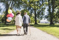 Casal sênior com balões passeando — Fotografia de Stock