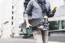 Businessman carrying skateboard — Stock Photo