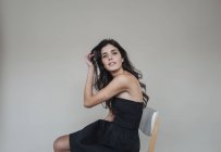 Donna dai capelli scuri seduta sulla sedia — Foto stock
