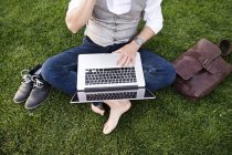 Empresário sentado na grama com laptop — Fotografia de Stock