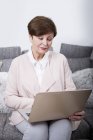 Mujer mayor usando laptop - foto de stock