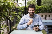 Человек с сотовым телефоном и стаканом пива — стоковое фото