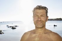 Uomo sorridente di fronte al mare — Foto stock