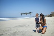 Junge Frau und Junge am Strand fliegen Drohne — Stockfoto