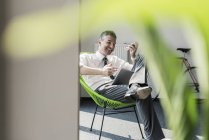 Homme d'affaires assis dans un fauteuil avec tablette — Photo de stock