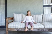 Little girl sitting on couch on terrace — Stock Photo