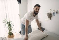 Jeune homme faisant le lit — Photo de stock