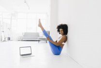 Woman practising yoga with laptop — Stock Photo
