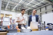 Men using laptop in factory — Stock Photo