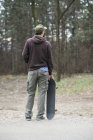 Uomo in piedi e in possesso di skateboard — Foto stock