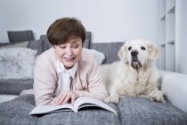 Seniorin liegt mit Hund auf Couch — Stockfoto