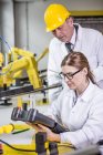 Dos ingenieros en fábrica mirando el dispositivo - foto de stock