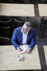 Homme d'affaires assis dans un café et écrivant dans un journal — Photo de stock