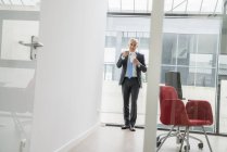 Geschäftsmann steht und isst Essen zum Mitnehmen — Stockfoto