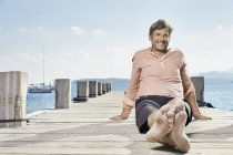Uomo seduto sul molo — Foto stock