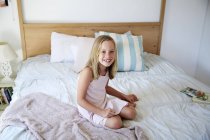 Little girl sitting on bed — Stock Photo