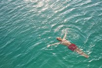 Человек, плавающий в бирюзовой воде — стоковое фото